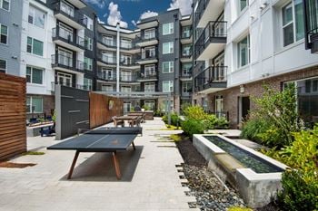 Furnished courtyard with ping pong table and benches in front of an apartment building